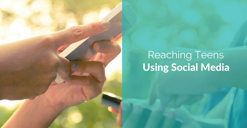 The image features two sections. On the left side, a close-up of hands holding a smartphone, with warm sunlight creating a soft, glowing background, suggesting outdoor activity and casual use of social media. On the right side, a teal overlay contains white text that reads, "Reaching Teens Using Social Media." The overall design conveys a message about how to effectively engage with a younger audience through social media platforms. The contrast between the natural, warm colors on the left and the digital feel on the right highlights the intersection of technology and social interaction in reaching teens.