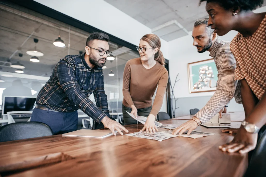 Group of professionals examining documents on a table in an office environment.