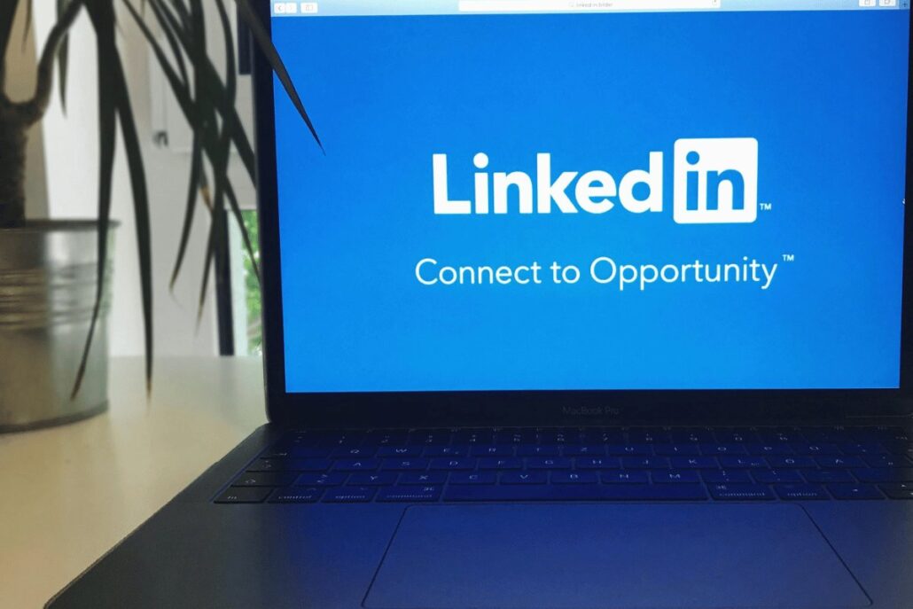 Laptop displaying LinkedIn homepage with slogan "Connect to Opportunity" on a desk with plant.