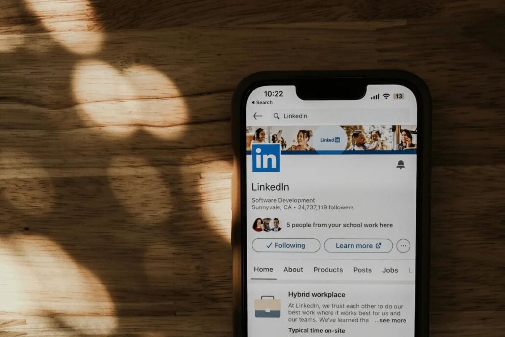 Mobile phone displaying LinkedIn's profile page with a wooden table background.