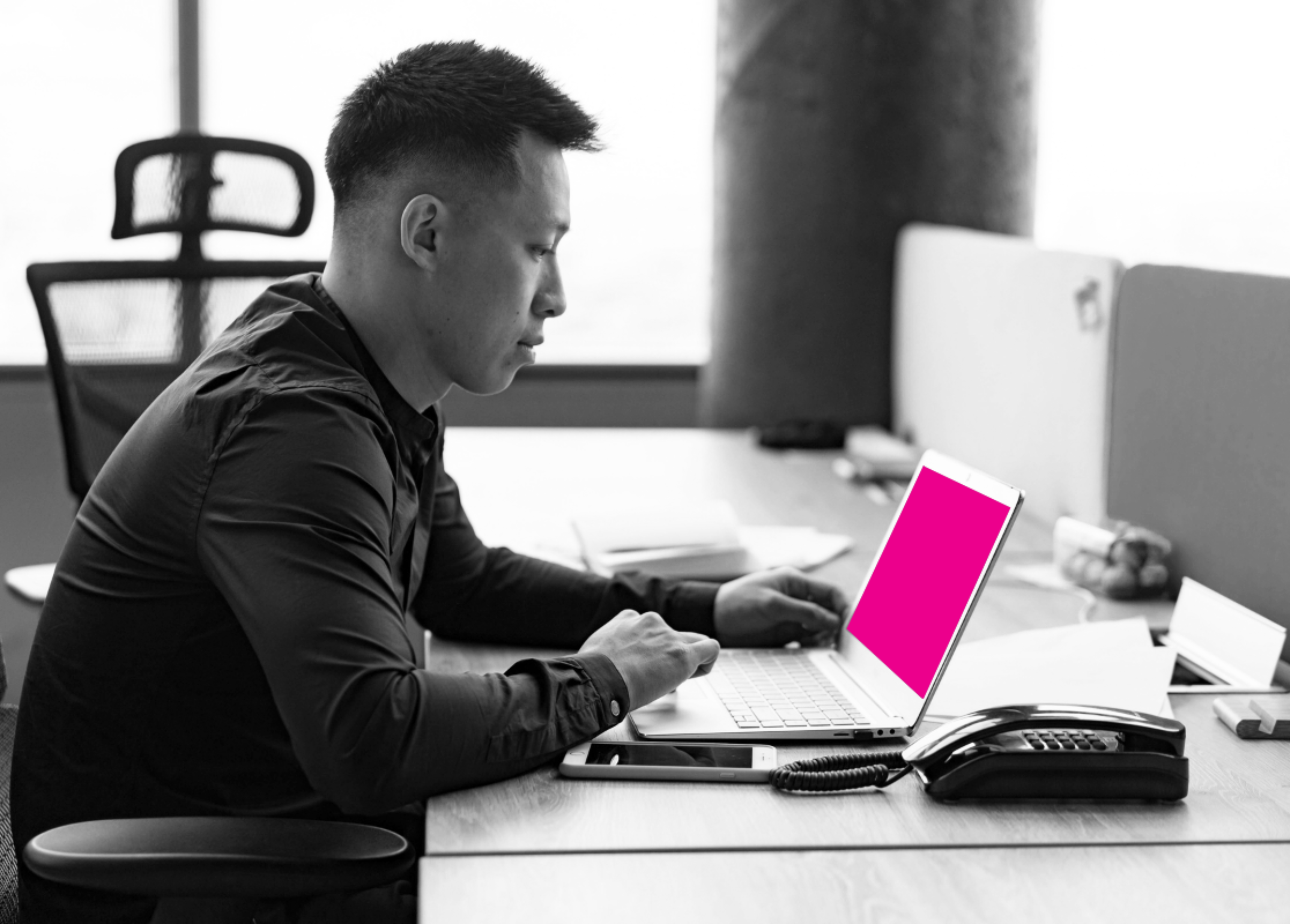 A focused professional working on a laptop in a modern office setting.