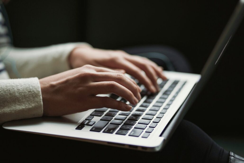 Close-up of hands typing on a laptop keyboard.