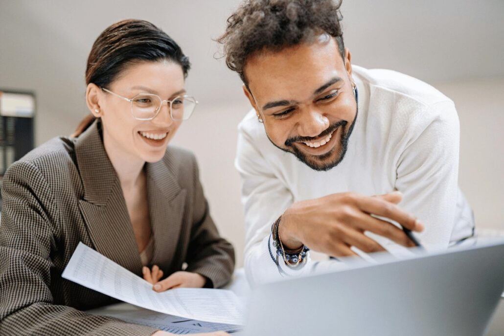 Two professionals reviewing documents together at a desk with a laptop.