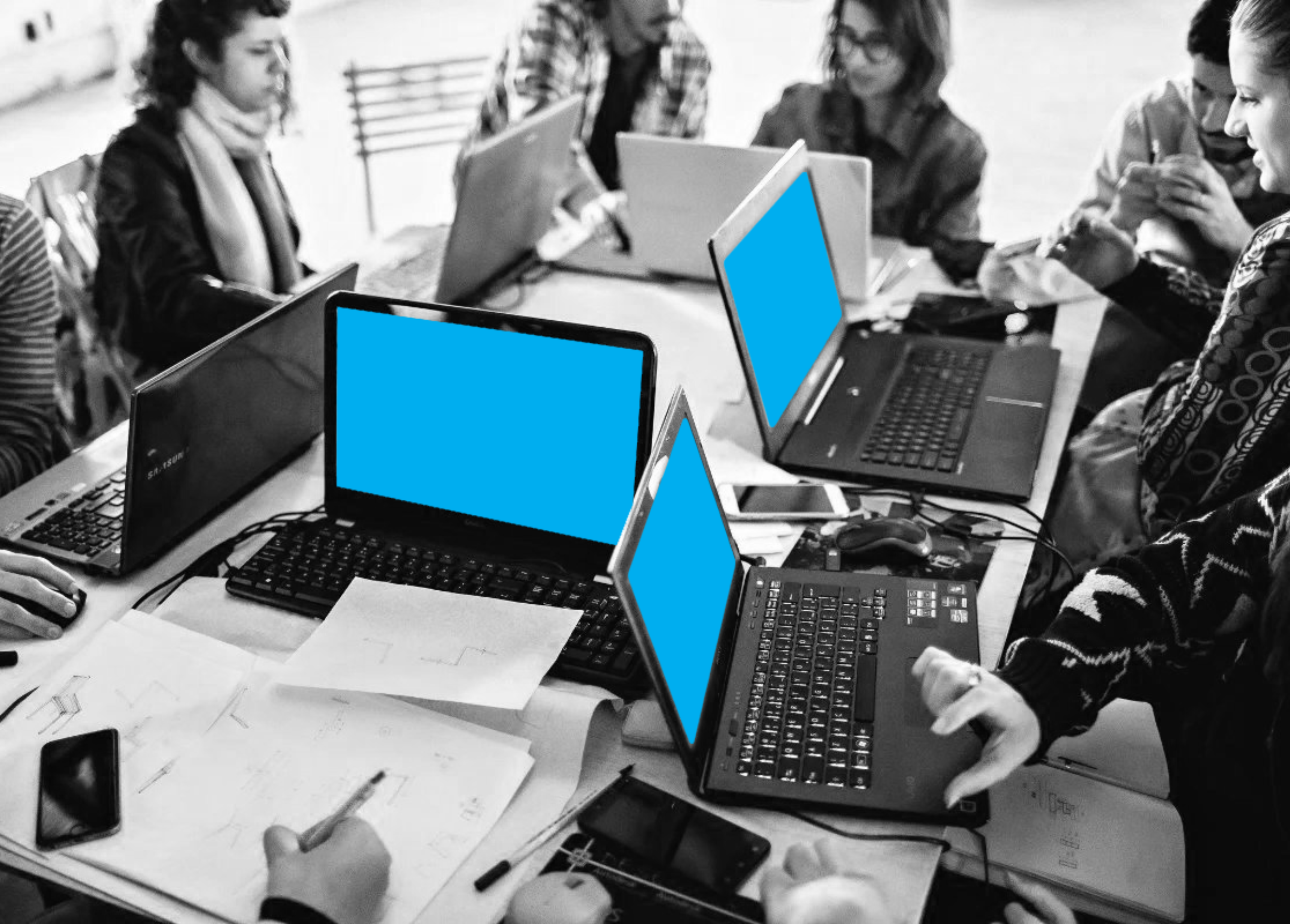 A collaborative workspace with multiple laptops and handwritten notes scattered across a table, suggesting a group project or meeting.