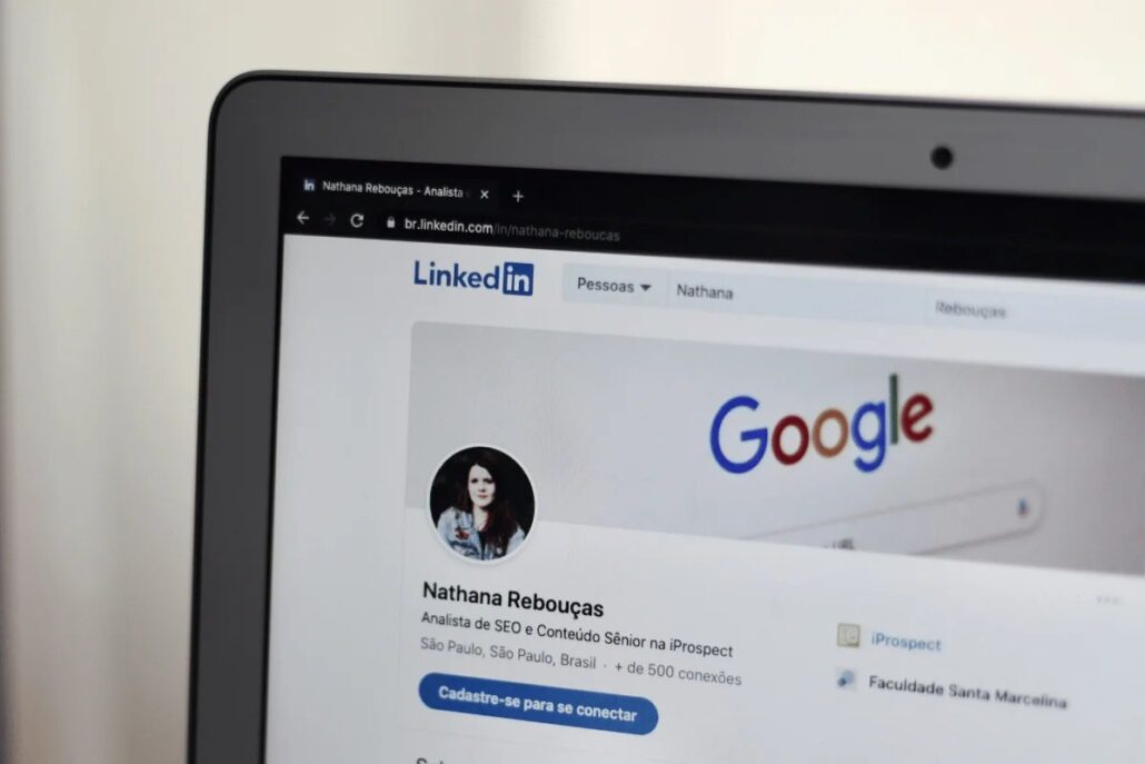 A laptop displaying a LinkedIn page in Portuguese for Nathana Rebouças, an SEO and content strategist, showing over 500 connections.