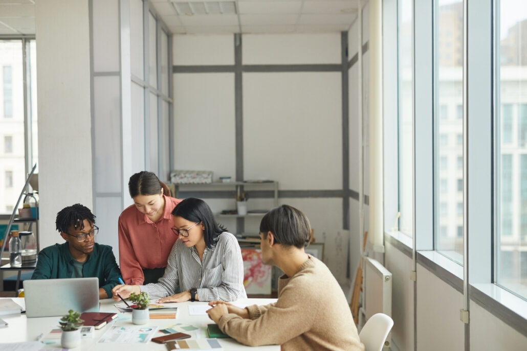 Group discussion with documents and a laptop in a bright workspace.