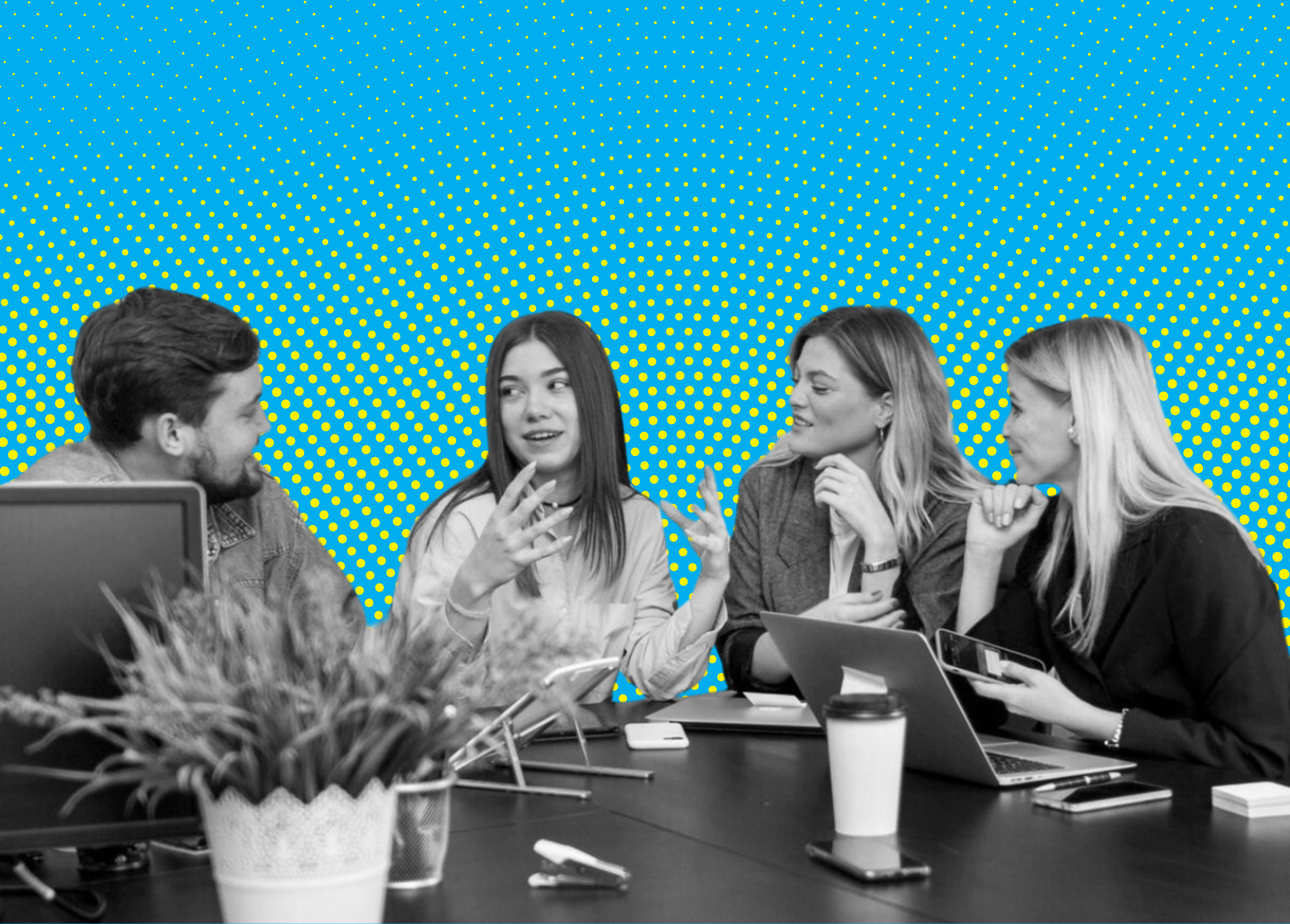A group of young professionals engage in a discussion around a conference table with laptops and a coffee cup, set against a vibrant background.