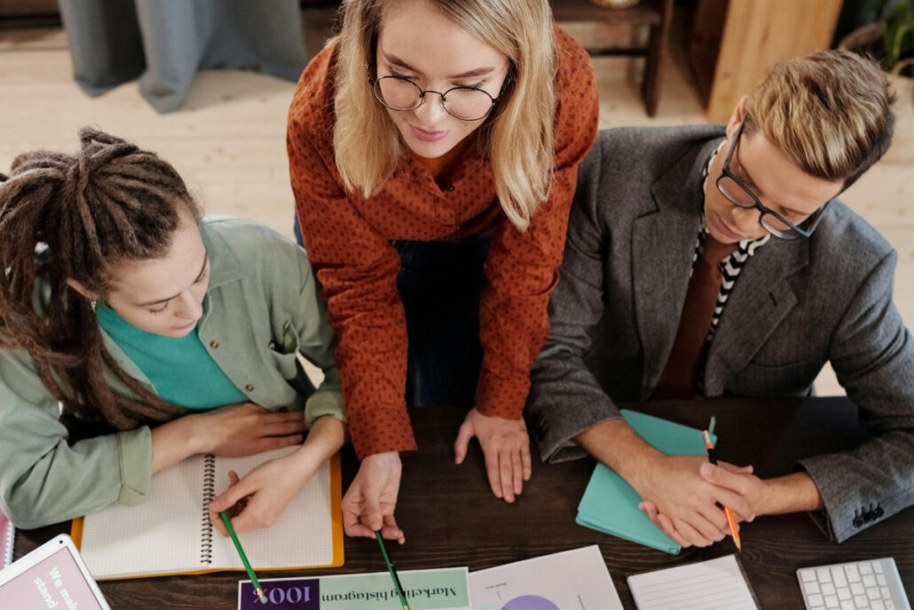 Three colleagues collaborating on a project, reviewing documents and notes on a table.