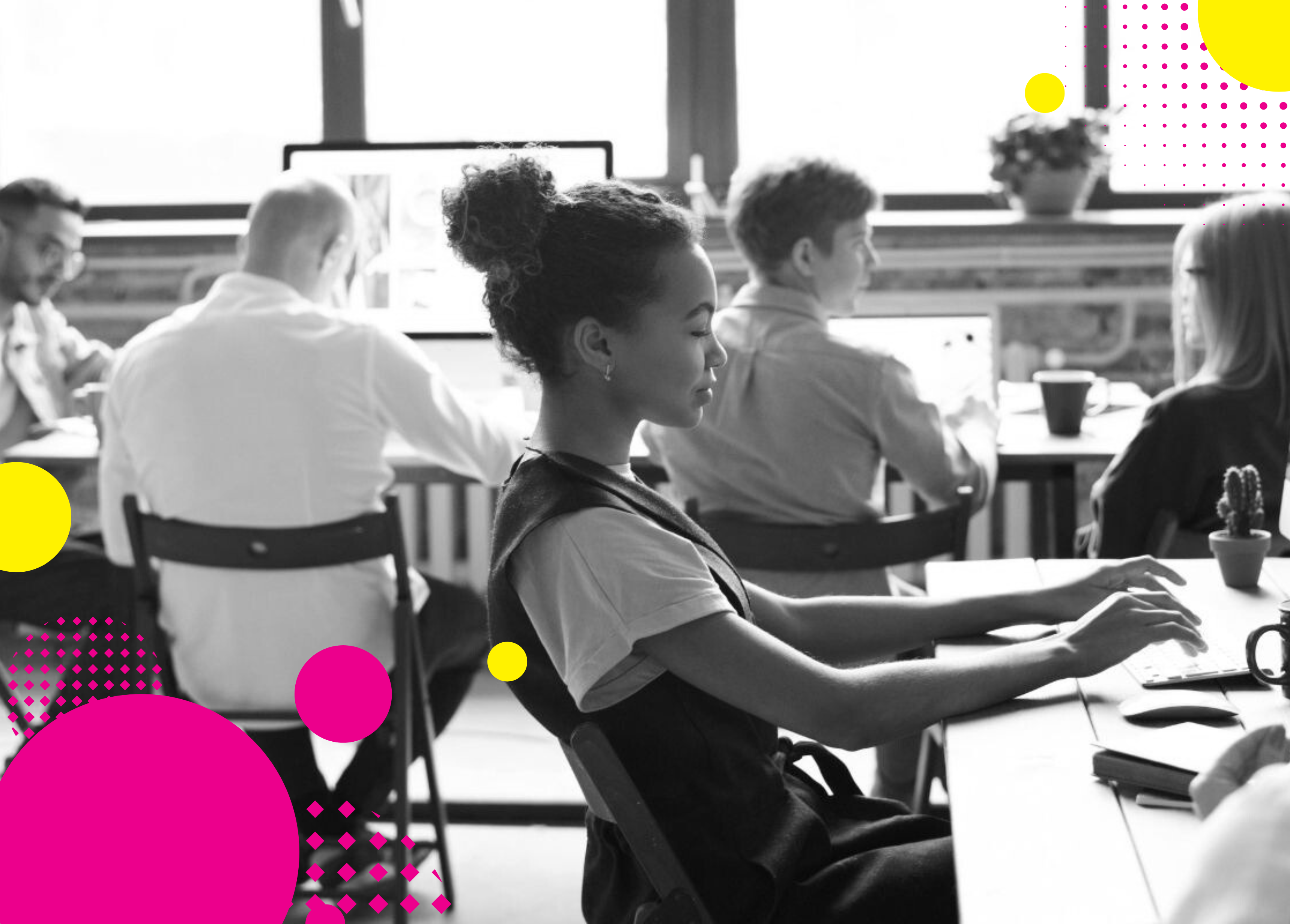 A group of people engaged in a collaborative workspace, focusing on computer screens with modern decor and colorful shapes in the foreground.