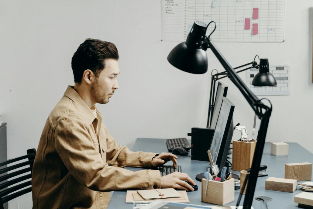 A person sitting at a desk, working on a computer in a modern office space.