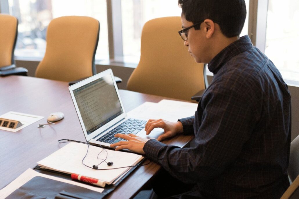 Professional working on laptop in a boardroom setting.
