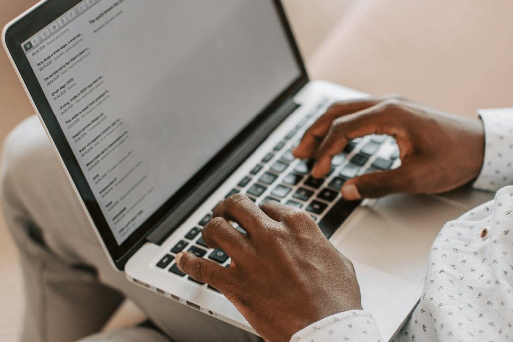 Hands typing on a laptop while checking email inbox.
