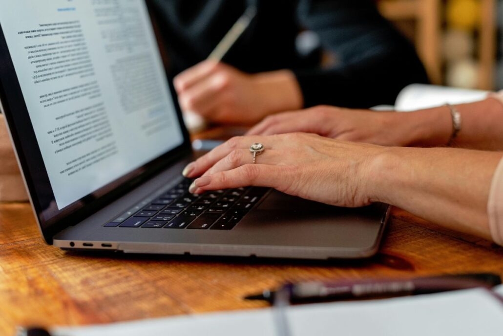 Close-up of woman typing on laptop keyboard.