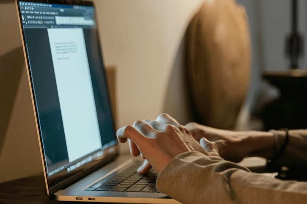 Person typing on laptop with blank document open.