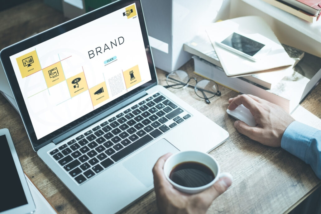 Person working on a laptop with "Brand" strategy displayed on the screen.
